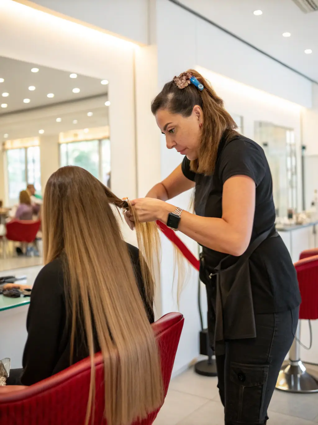 A close-up shot of a stylist applying keratin bond extensions to a client's hair in a salon setting, showcasing precision and natural integration.